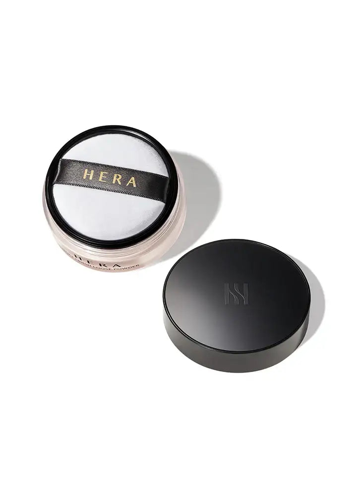 Hera loose setting powder with black lid and gold logo, ideal for flawless makeup finish