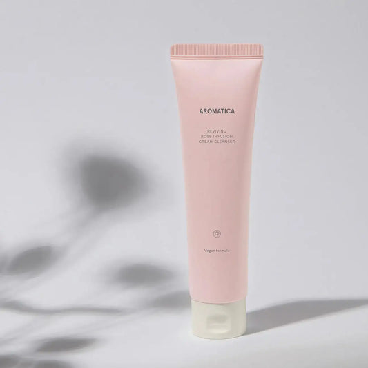 Aromatica Reviving Rose Infusion Cream Cleanser, vegan formula, soft pink tube with leaf shadow backdrop