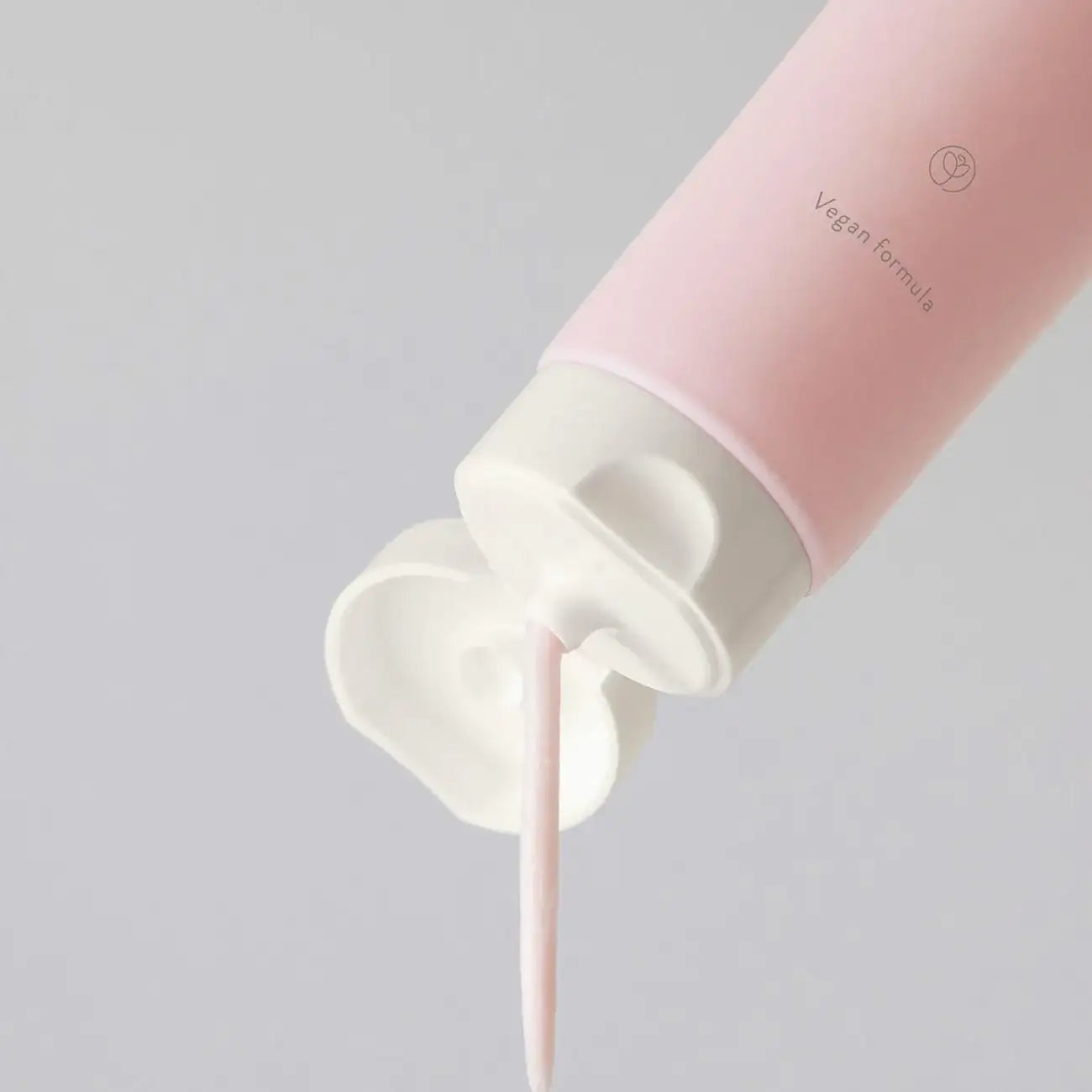 Pink skincare tube dispensing vegan formula, gentle cleanser or moisturizer for radiant skin routine