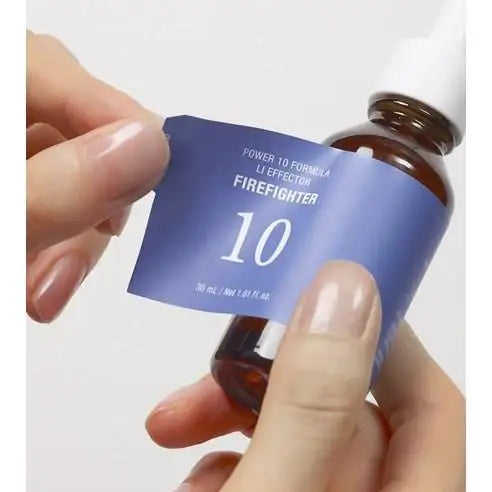 Firefighter 10 skincare serum bottle with blue label, held in hand for application