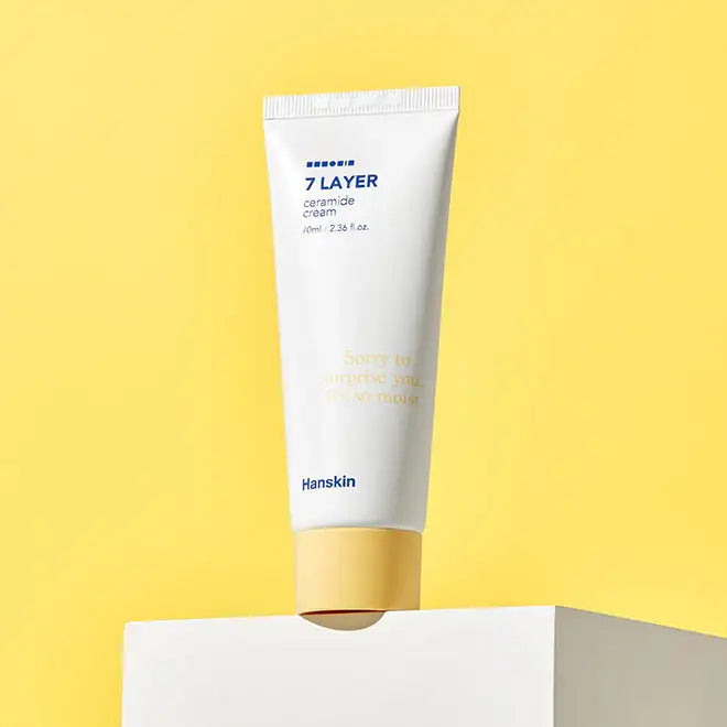 Hanskin 7 Layer Ceramide Cream tube on white block against yellow background, hydrating skincare product