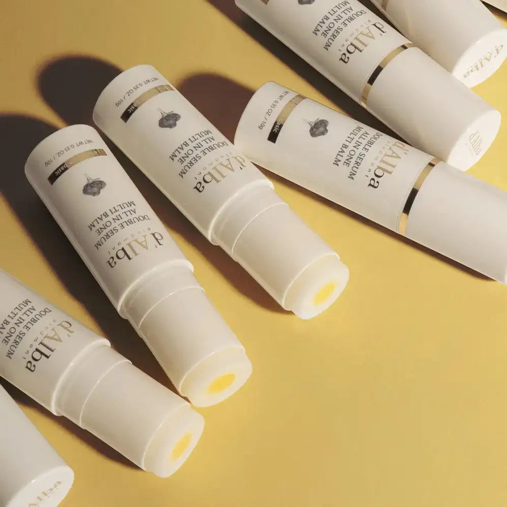 d'Alba Double Serum All-in-One Multi Balm tubes on yellow background, skincare wellness product