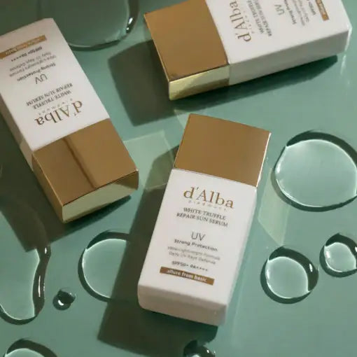 d'Alba White Truffle Repair Serum with UV protection, shown with water droplets on a green surface