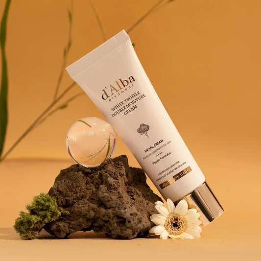 d'Alba White Truffle Double Moisture Cream tube with floral and rock accents on warm background